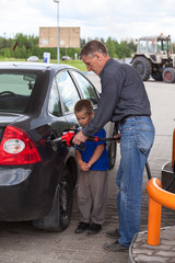 Father with son refueling car on gas station together