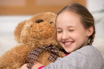Cute girl with toy bear. Cheerful little girl hugging toy bear a