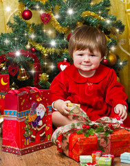 bambina sorridente che apre i regali di Natale