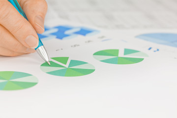 Hand with Pen working on Graphs and Pie Chart