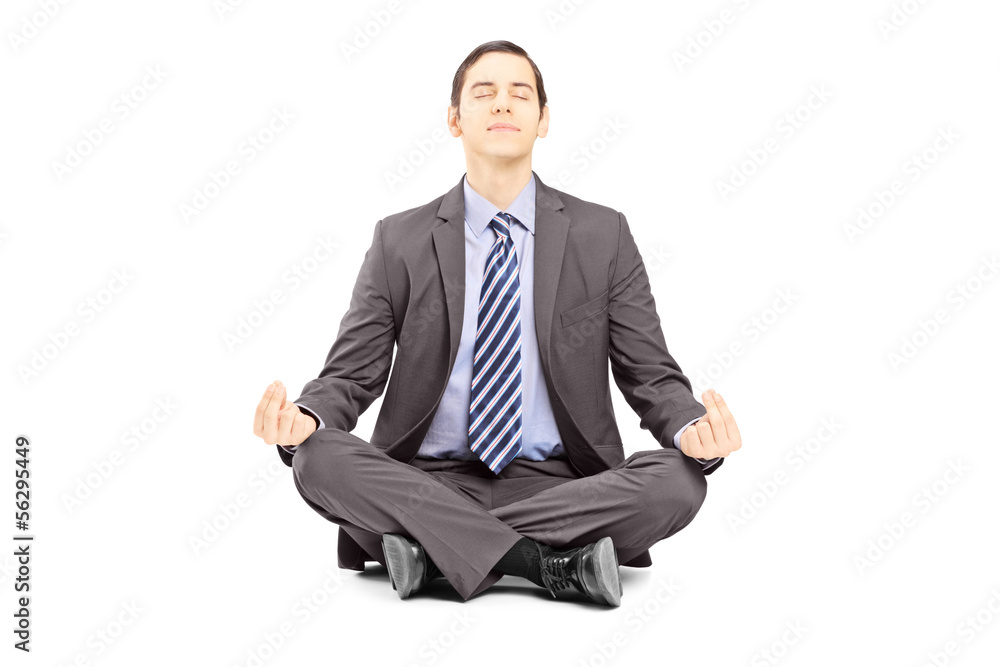 Poster Young businessman in suit sitting on a floor and meditating