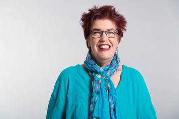 Happy smiling middle aged woman with red short hair and glasses.