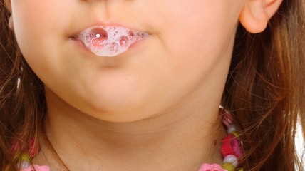Close up little girl doing fun saliva bubbles - obrazy, fototapety, plakaty