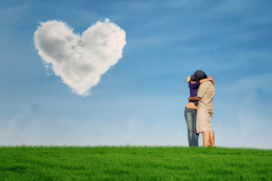 Couple kissing under heart shape cloud