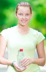 Woman drinking cold mineral water from a bottle after fitness ex