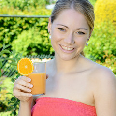 Frau trinkt Orangensaft im Garten