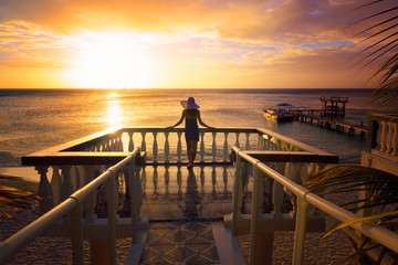 A woman in a hat looking at the romantic Caribbean sunset