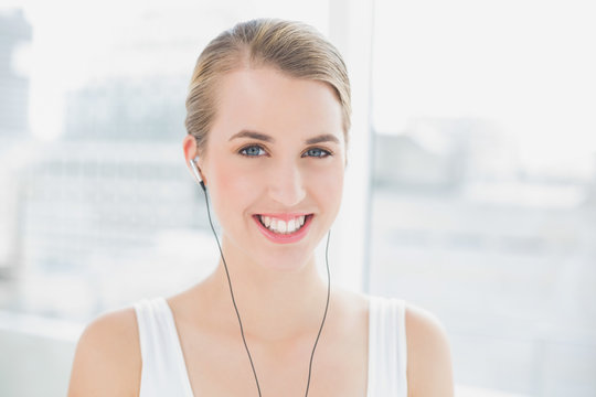 Head shot of cheerful sporty woman listening to music
