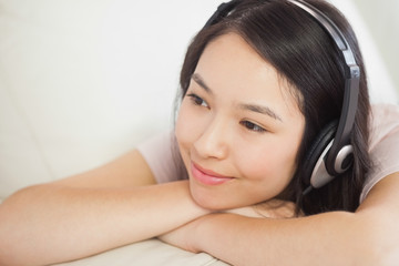 Relaxing asian girl lying on the sofa and listening to music