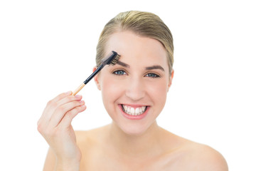 Fototapeta premium Smiling attractive blonde using eyebrow brush
