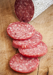 Fresh pork salami on wooden background close up