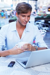 Fototapeta premium Handsome young man with laptop in summer cafe