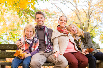 Fototapeta premium Happy Family outdoors sitting on bench in autumn