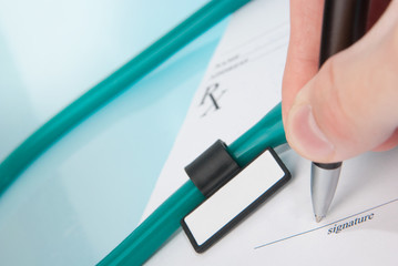 Doctor filling in empty medical prescription with stethoscope