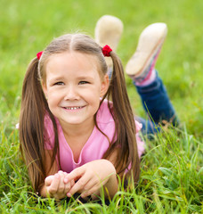 Portrait of a little girl laying on green grass