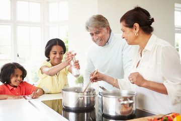 Grandparents And Grandchildren Cooking Meal At Home