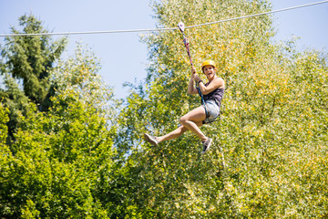 Happy Woman Hanging On Zip Line In Forest