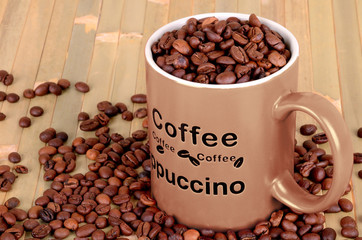 brown cup with coffee beans is on a wooden table