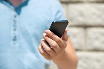 boy holding a touch phone against a wall
