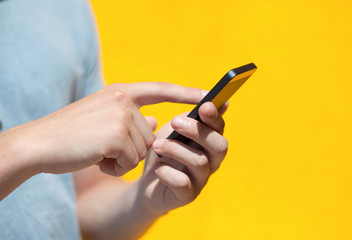 boy holding a phone and a touch screen against a yellow wall