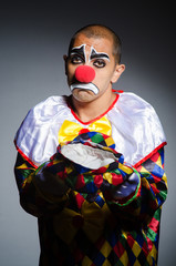 Sad clown against dark background