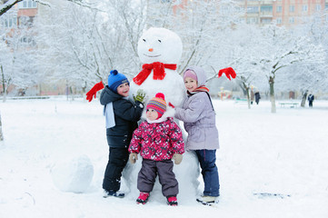 Children building snowman in garden