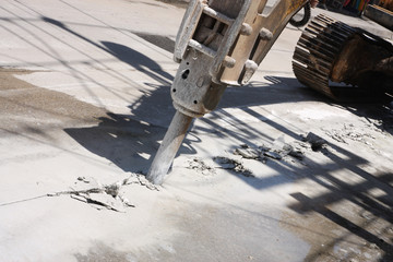 Excavator breaking street asphalt with hydrohammer drill