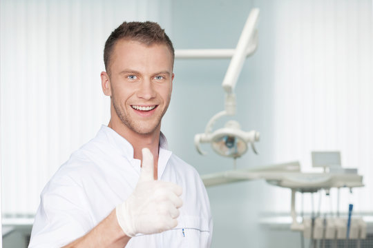 Cheerful dentist. Smiling young dentist in protective gloves loo