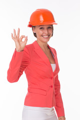 Business woman in helmet and jacket show Okay isolated on white