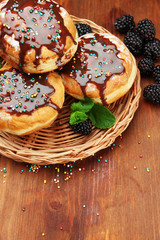 Tasty donuts with chocolate and berries on wooden table