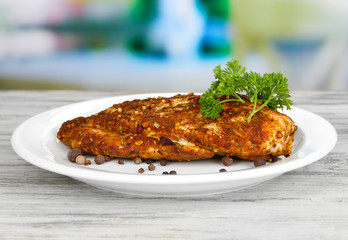 Roasted chicken fillets on white plate on bright background
