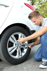 Man driver having trouble at road changing wheel