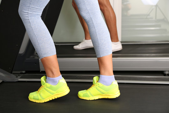 Women and men feet on treadmill close-up