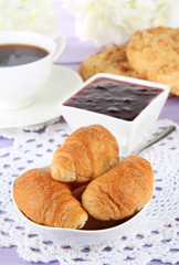 Tasty croissants and cup of coffee on table close-up