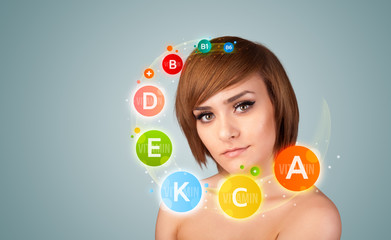 Pretty young girl with colorful vitamin icons and symbols