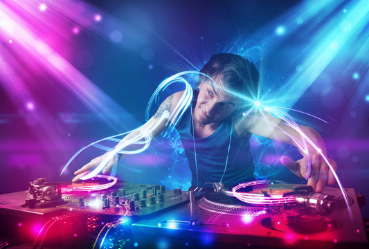 Energetic Dj mixing music with powerful light effects