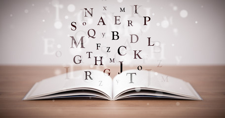 Opened book with flying letters