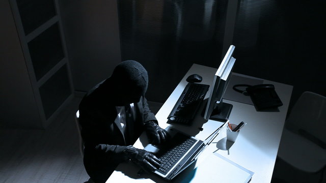 Young male thief stealing data from computer