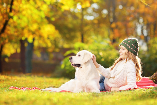 Female lying on a grass with her dog in a park