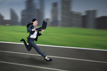 Asian businesswoman running with laptop