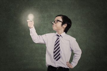 Confident business kid holding lit bulb