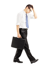 Disappointed businessman walking with briefcase