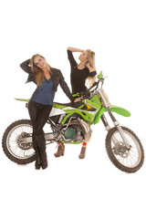 Obraz na płótnie Canvas Two women posing by a dirt bike