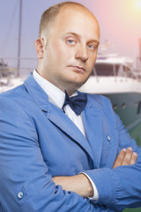 Man in Suite and Bow Tie Against Luxury Yacht