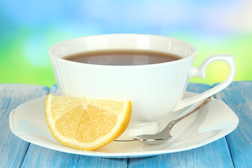 Cup of tea with lemon on table on blue background