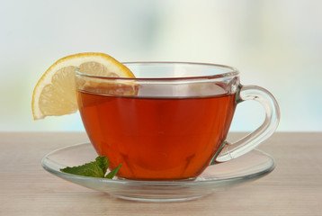 Cup of tea with lemon on table on light background