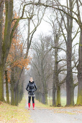 Fototapeta premium woman wearing rubber boots in autumnal alley