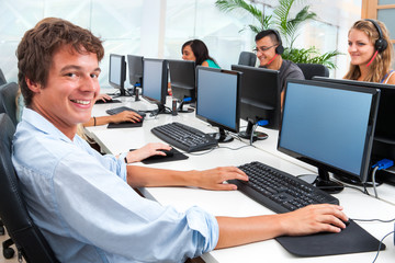 Young student working on computer in office.