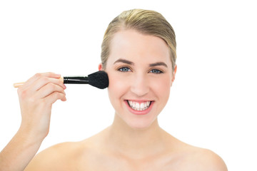 Fototapeta premium Smiling attractive blonde using blusher brush