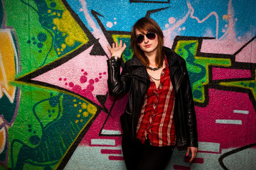 Fashionable girl and colorful graffiti wall